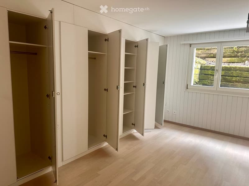 White cupboards, empty shelves, window, power outlets, wooden floor