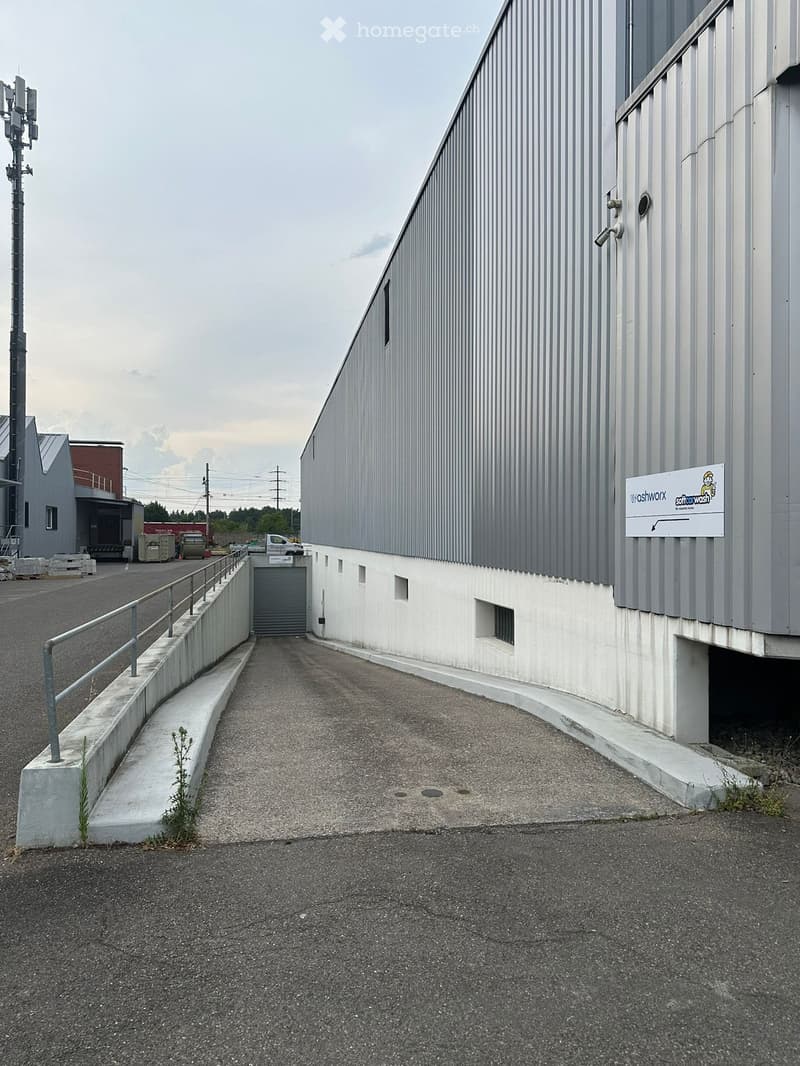 A modern industrial building with a grey metal facade, a raised entrance ramp, and a sign reading "washworx" on the wall.