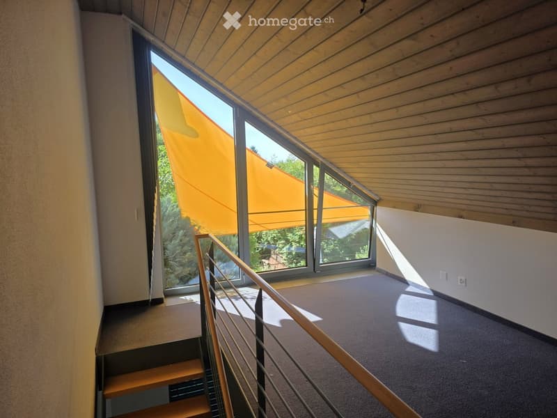Modern hallway with wooden staircase, metal railing, large windows with orange blinds, and carpeted floor.