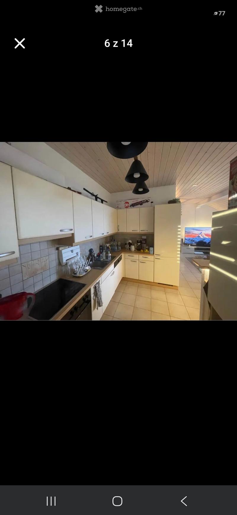 Modern kitchen with white cabinets, stainless steel appliances, and a central island. Features include a sink, stove, oven, refrigerator, and various kitchen items on the counter.