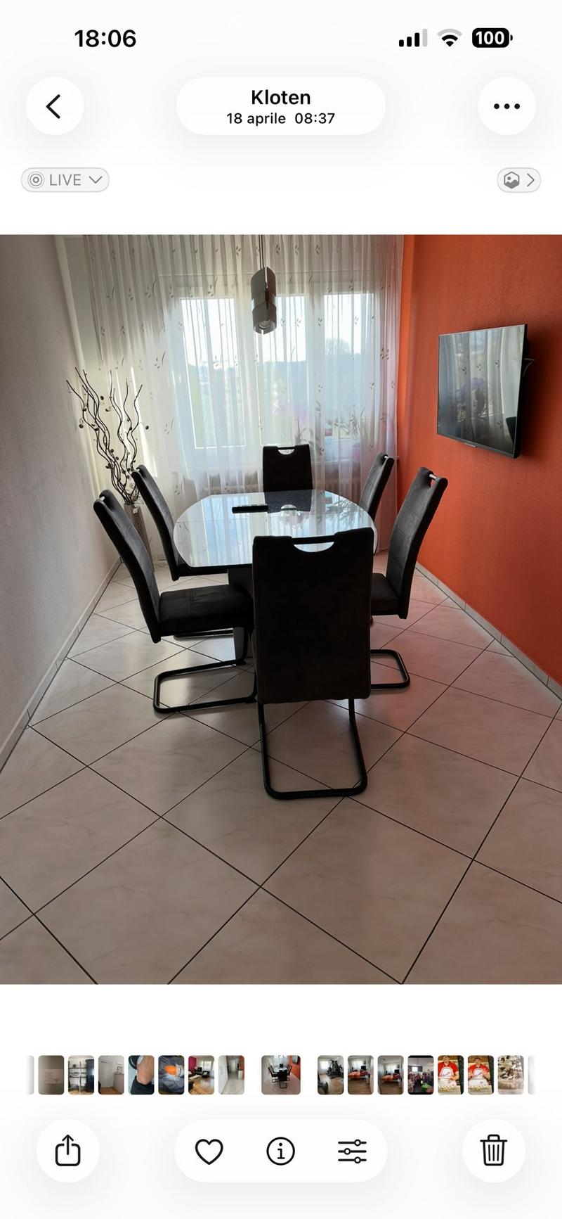 Dining area with a glass table, black chairs, and a mounted television on the wall.