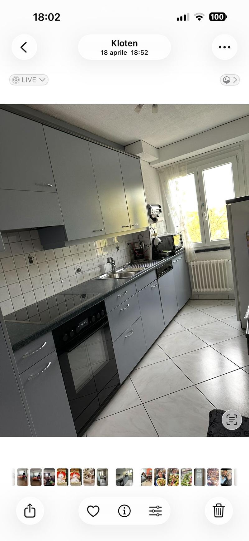 Modern kitchen with grey cabinets, a black oven, microwave, sink, and tiled backsplash.