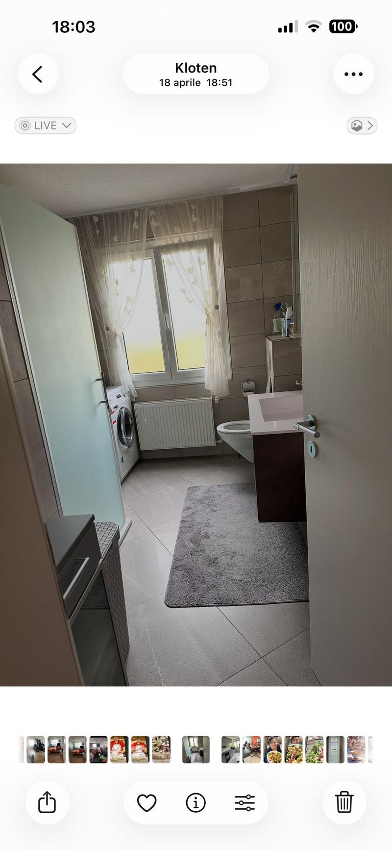 Modern bathroom with tiled walls, a sink, toilet, washing machine, radiator, and a small rug on the floor.