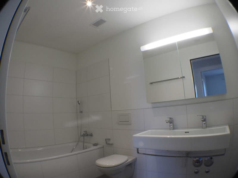 modern bathroom with white tiles, bathtub, toilet, sink, mirror, and shower head