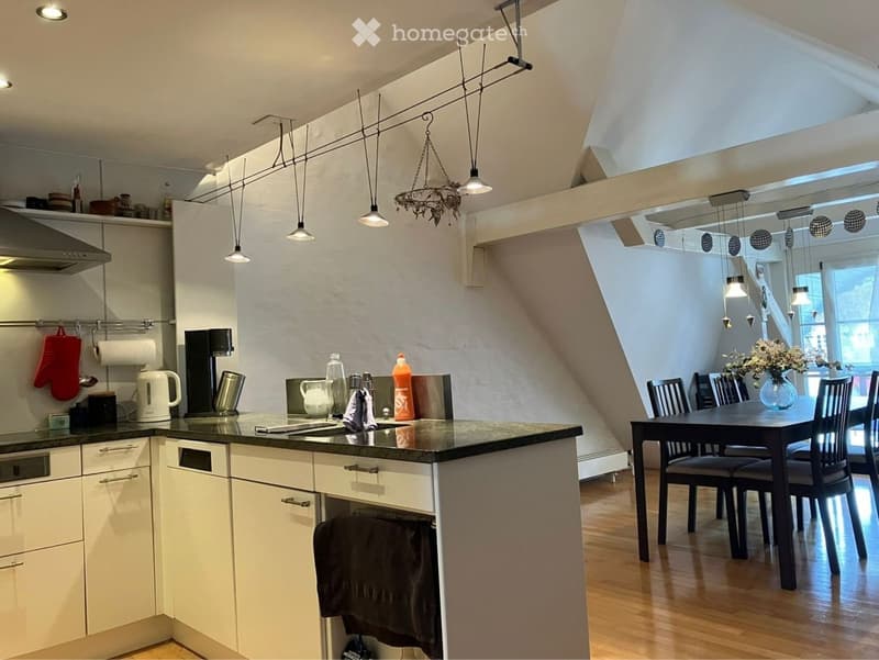 Modern kitchen with a central island, dining area, and pendant lighting. Includes a coffee maker, oven, and various kitchen items.