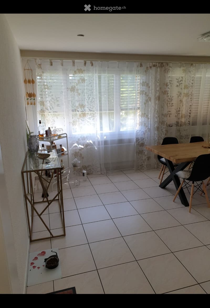Dining area with a wooden table, black chairs, a bar cart with bottles, and a curtained window.