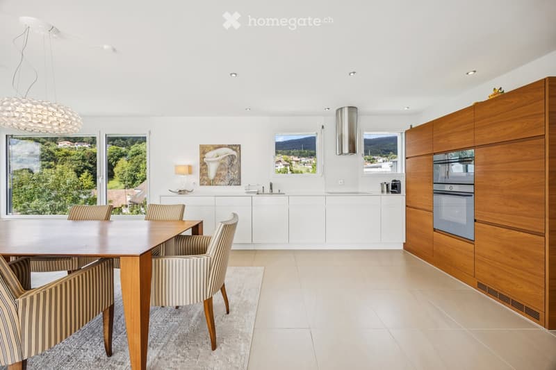 Kitchen. Modern kitchen with white cabinets, wooden dining table, striped chairs, large windows with scenic view, and a hanging light fixture.