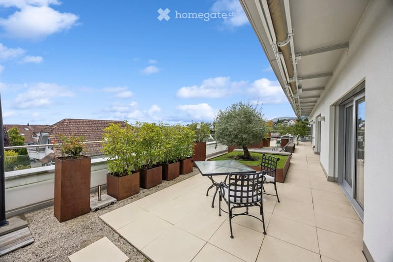 Balcony / Terrace. Balcony with tiled floor, glass table, two black metal chairs, and several potted plants arranged along the edge.