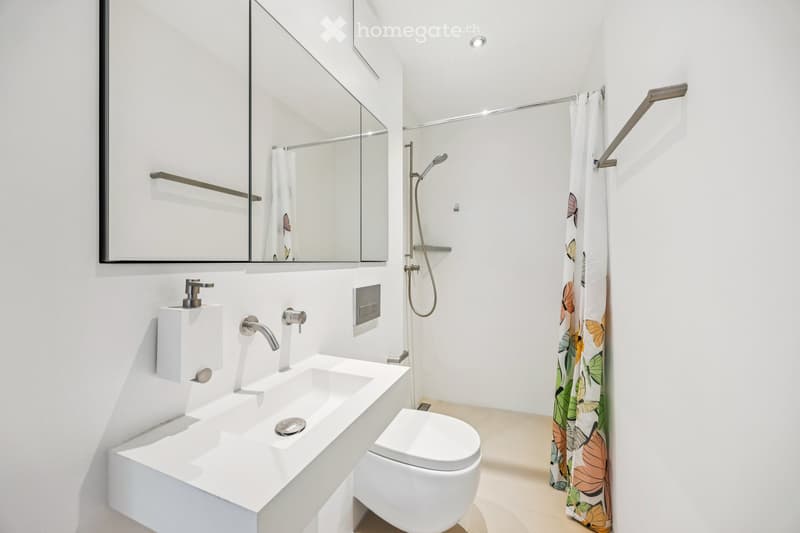 Bathroom. Modern bathroom with white walls, a large mirror, a double sink, a toilet, and a shower with a decorative curtain.