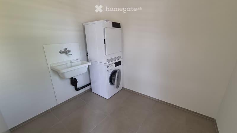 Bathroom with a white sink, faucet, and a stacked washing machine and dryer unit.