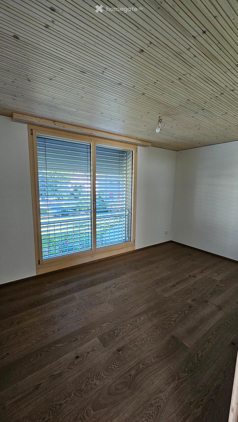 Empty room with wooden flooring, white walls, and large window with blinds. No furniture or equipment present.