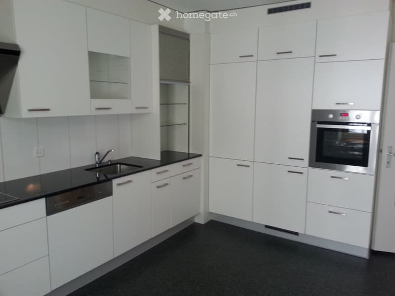 Modern kitchen with white cabinets, black countertops, a sink, and an oven.