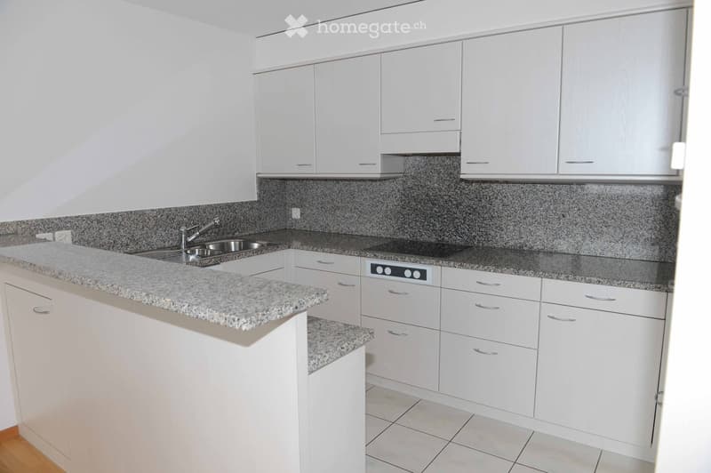 Modern kitchen with white cabinets, granite countertops, and stainless steel sink and stove.