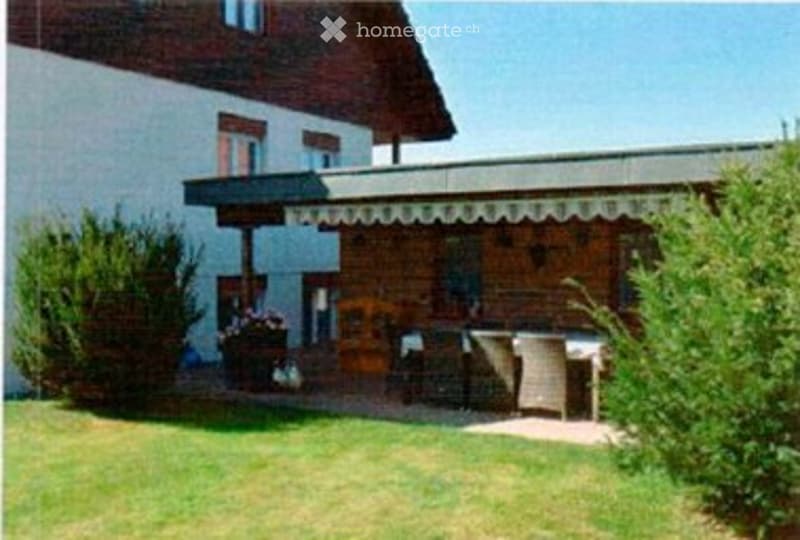 A well-maintained garden area with a covered patio, outdoor furniture, and lush greenery.