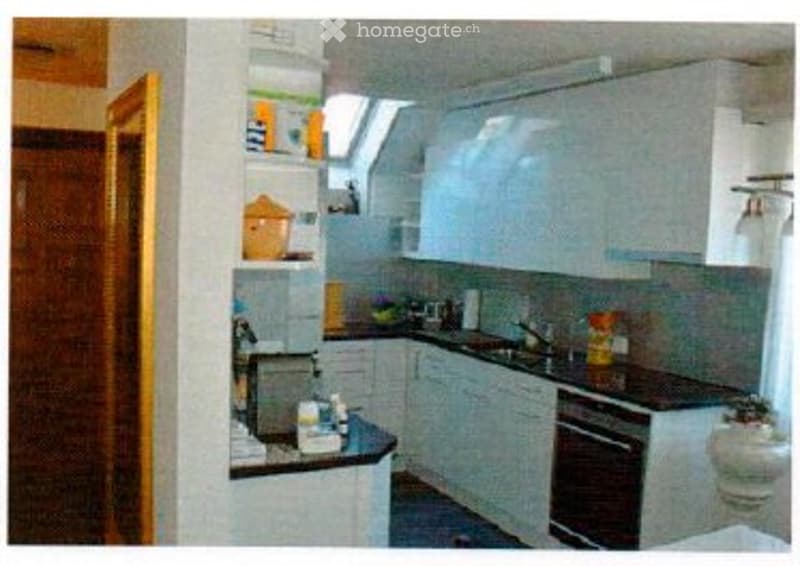 Modern kitchen with white cabinets, black countertops, and stainless steel appliances including a sink, oven, and microwave. The space features a window above the sink and a light fixture on the wall.