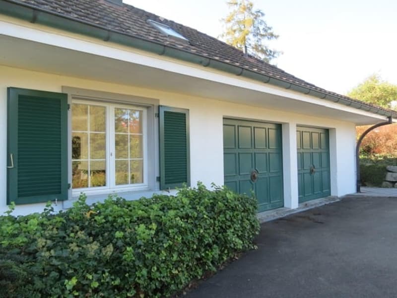 Single-story house with white exterior, green shutters, and a double garage.
