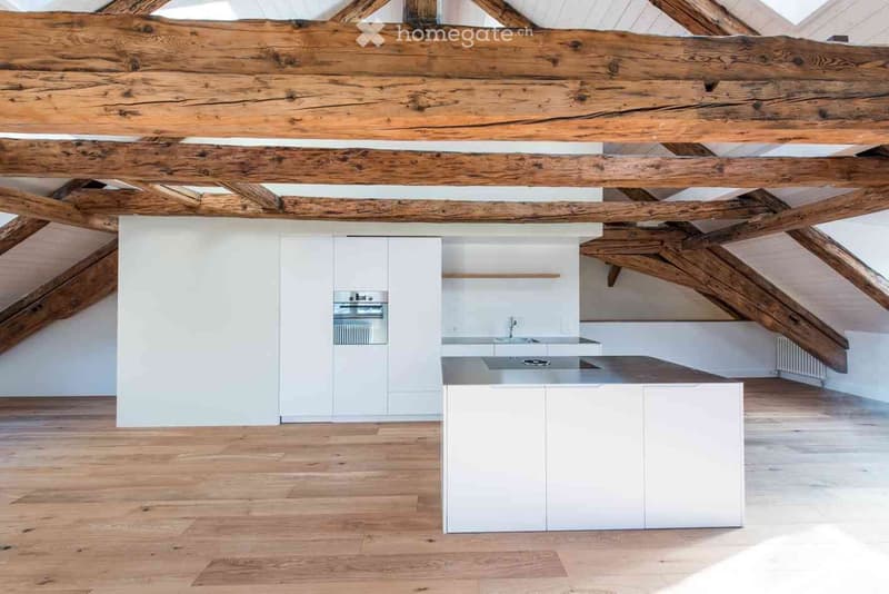 Modern kitchen with white cabinets, a central island, and exposed wooden beams on the ceiling.