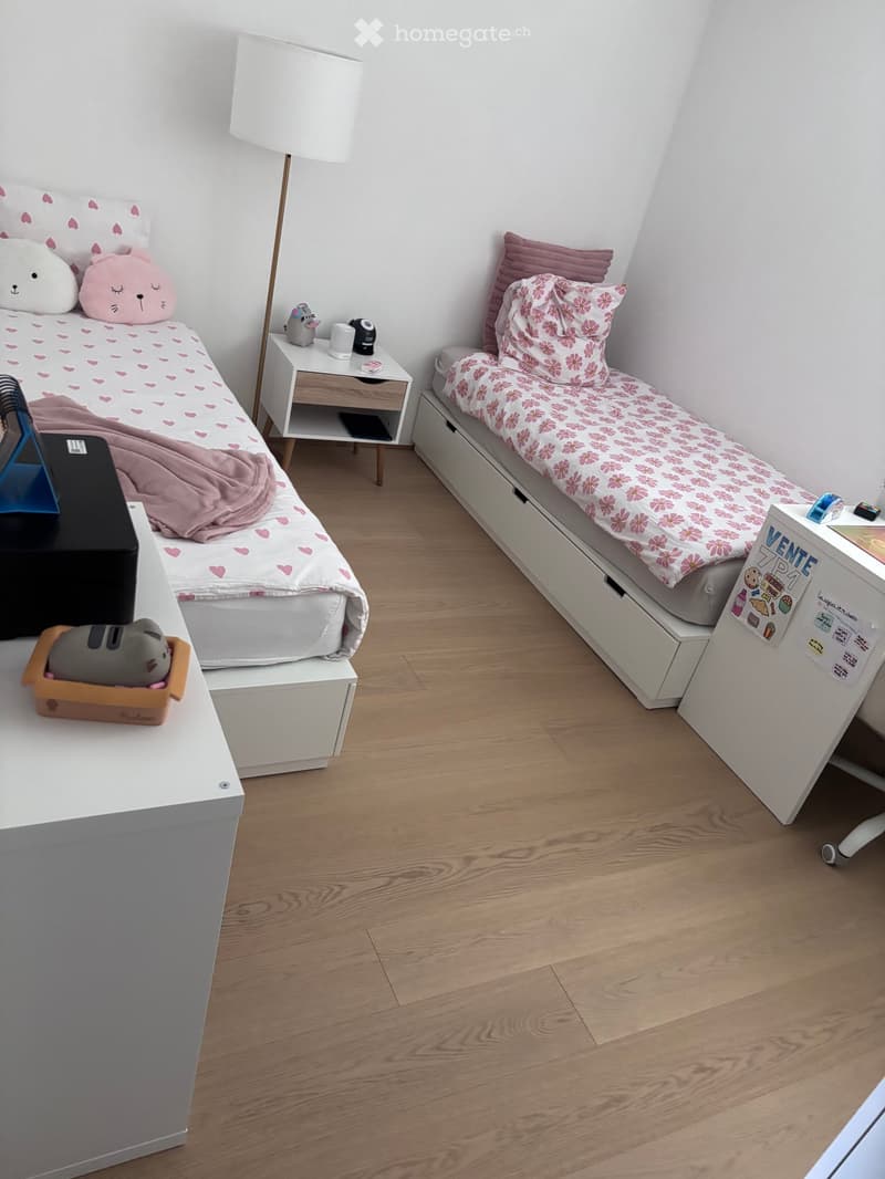 Cozy twin-sized bedroom with two beds, nightstands, and decorative pillows.