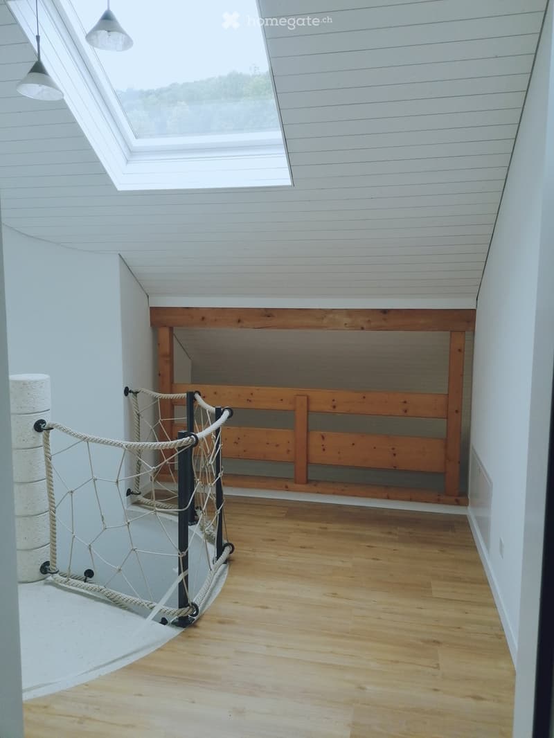 Bright, airy hallway with wooden flooring, white paneled walls, and a skylight window at the top. Features a rope railing and a built-in wooden bench along one wall.