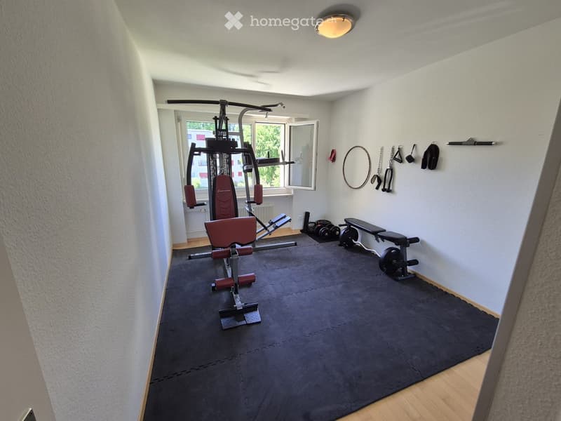 Well-equipped home gym with a multifunctional machine, bench, weights, and various fitness accessories.