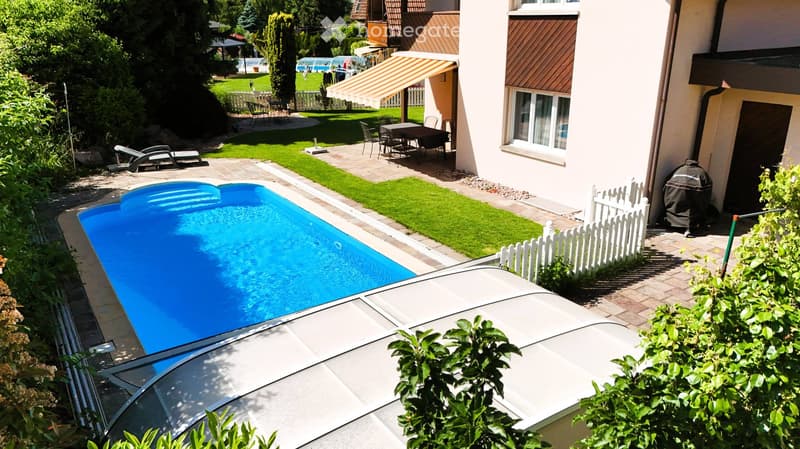 Private garden with a swimming pool, lounge chairs, outdoor dining set, and surrounding greenery.