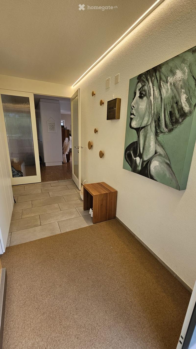Hallway with beige carpet, wooden bench, artwork, and a key holder labeled "HOME KEYS" on the wall.