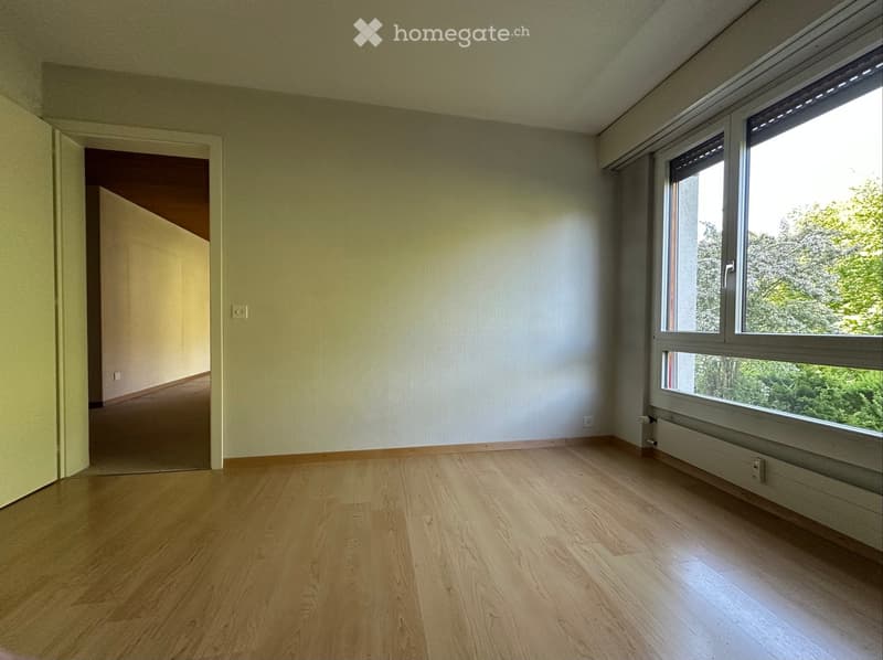 Empty room with light-colored walls, wooden flooring, and large windows letting in natural light. No furniture or equipment is present.