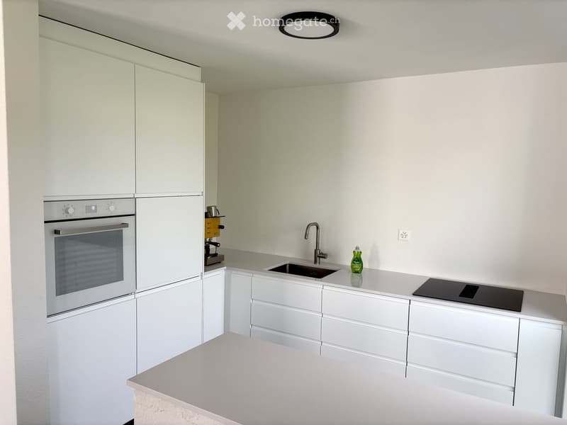 Modern kitchen with white cabinets, stainless steel appliances, and a sleek countertop.