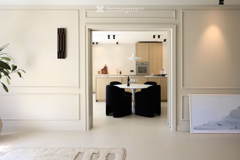 modern dining area with white walls, black chairs, white table, wooden cabinets, kitchen area with oven, countertop, sink, and faucet