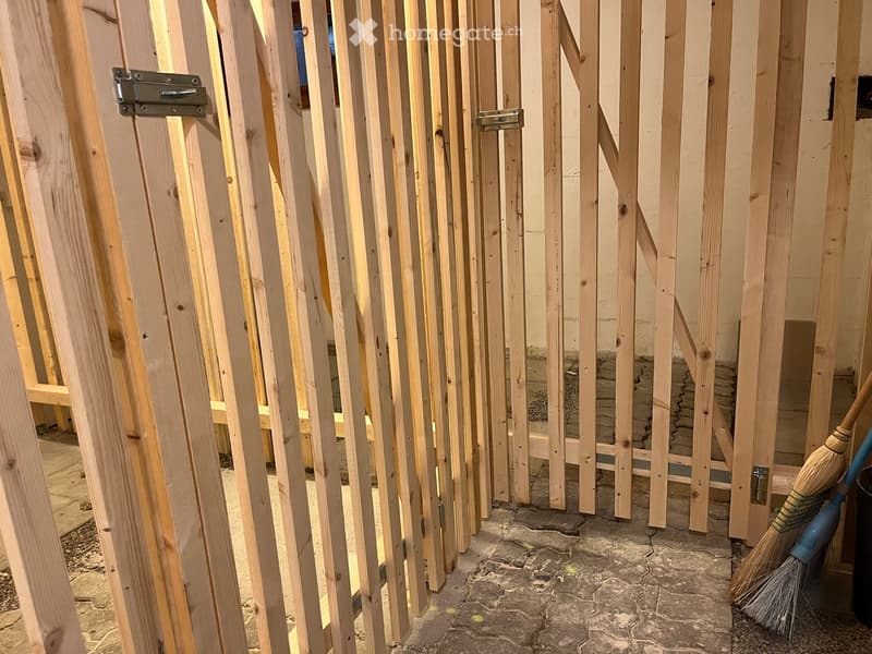Empty room with unfinished wooden walls and a broom in the corner.