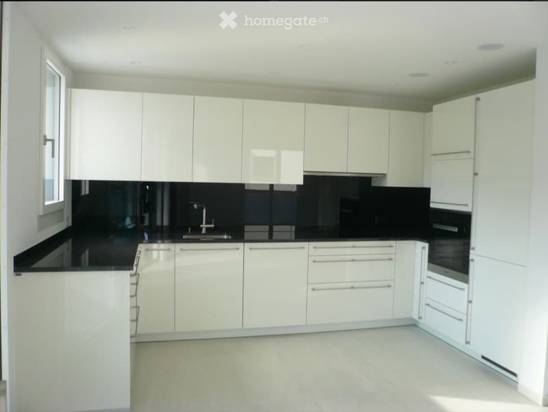 Modern kitchen with white cabinets, black countertops, and stainless steel appliances.
