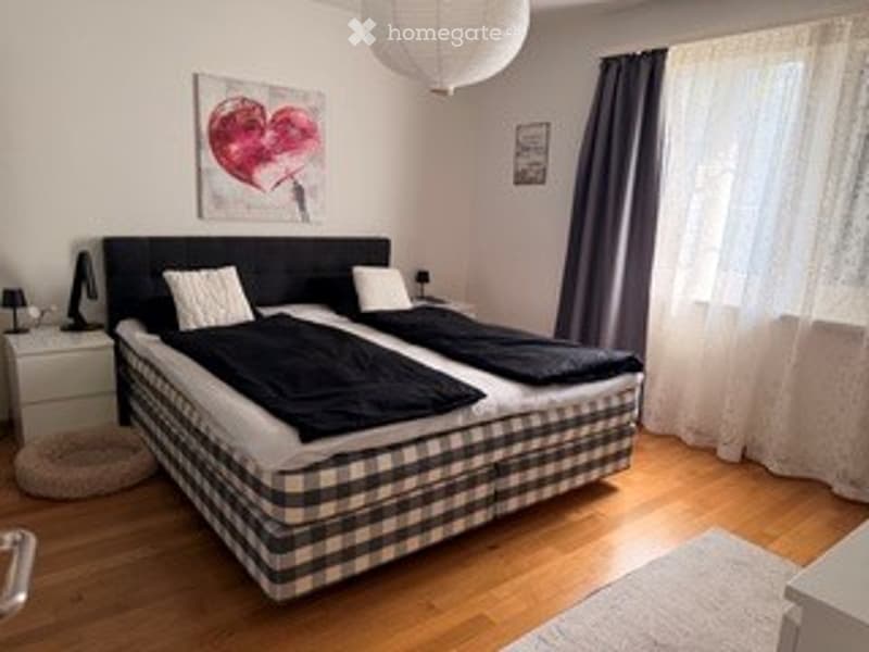 Cozy bedroom with a double bed, nightstand, lamp, and artwork on the wall.