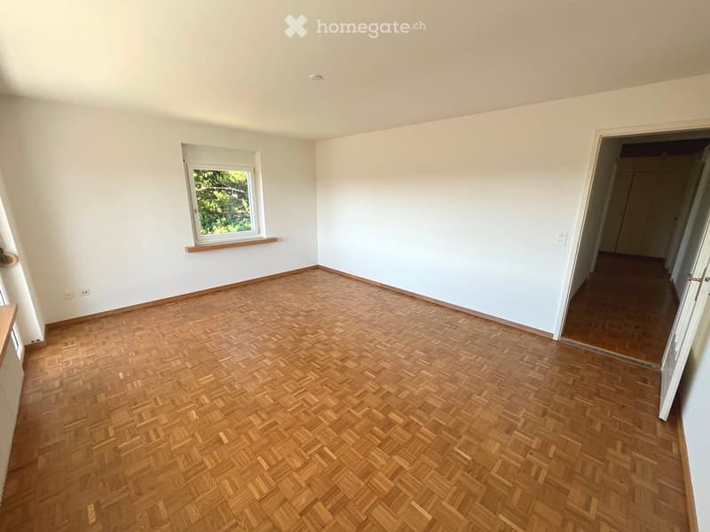 Empty room with wooden herringbone flooring, white walls, and a single window with a wooden sill. No furniture or equipment present.