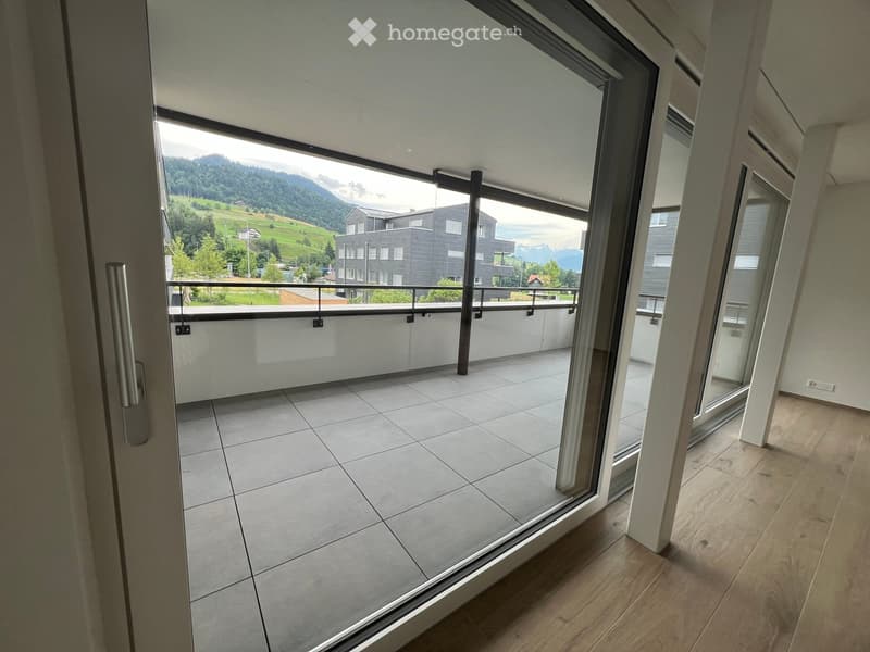 Balcony with tiled floor, glass sliding doors, metal railing, and scenic mountain view.