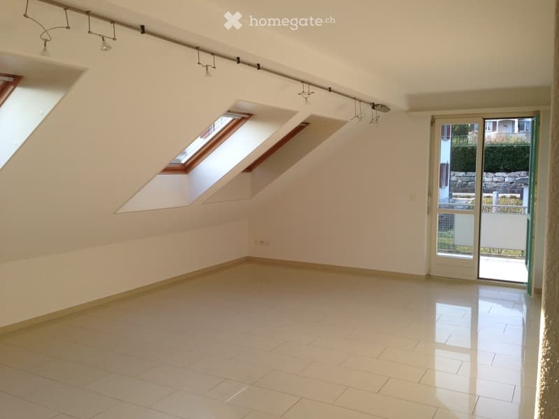 Empty room with white walls, tiled floor, and skylights, featuring a sliding glass door leading to an outdoor area.