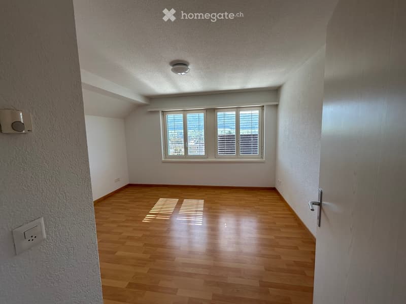Empty room with wooden flooring, white walls, and large windows with blinds. No furniture or equipment present.