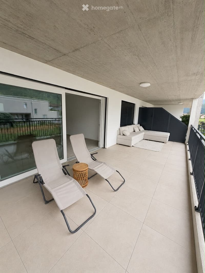Balcony with modern furniture including a white sofa, two lounge chairs, and a small round table.