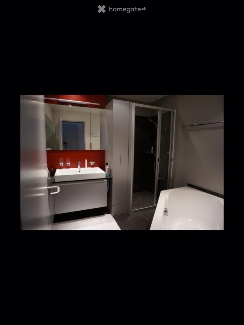 Modern bathroom with a white sink, bathtub, glass shower enclosure, and mirrored cabinet.