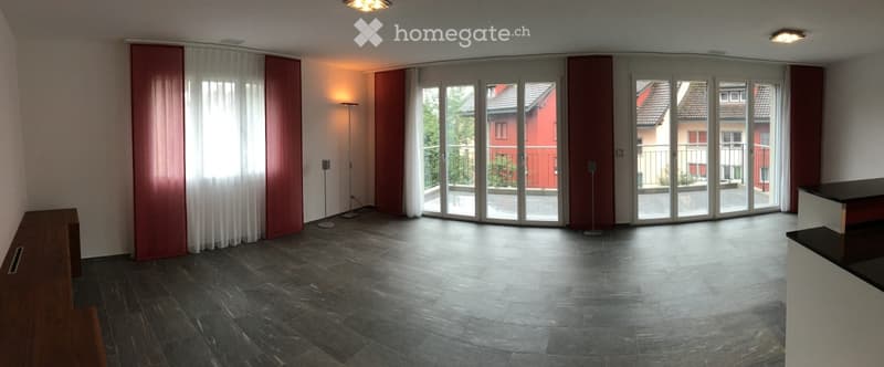 Open-plan unfurnished room with large sliding glass doors leading to a balcony, dark tiled floor, white walls, and minimal decor.