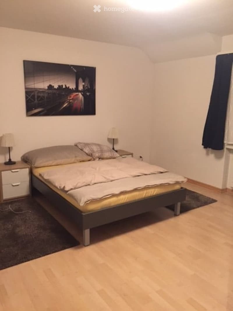 Cozy bedroom with a double bed, nightstands, lamps, and a large cityscape picture on the wall.