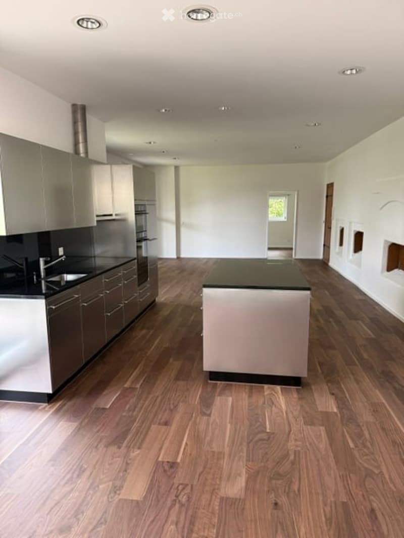 Modern kitchen with wooden flooring, stainless steel appliances, and a central island.