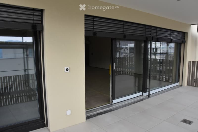 Balcony with sliding glass doors, tiled floor, and metal railings.