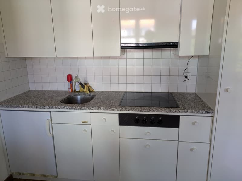 Modern kitchen with white cabinets, granite countertop, electric stove, and sink.