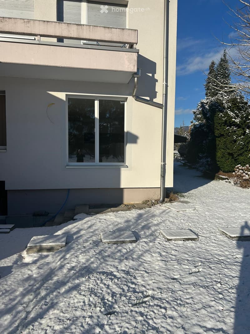 white exterior, concrete steps, balcony with railings, window, clear blue sky, snowy ground