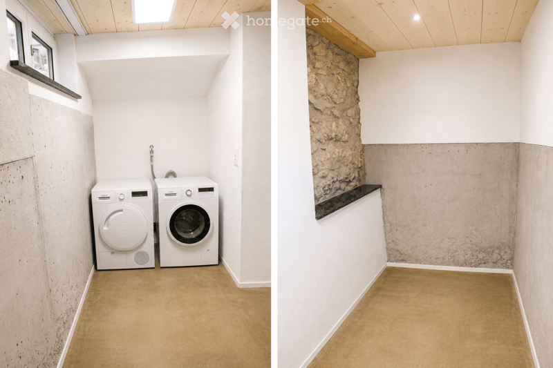 Modern bathroom with white washing machine and dishwasher, concrete walls, and wooden ceiling.