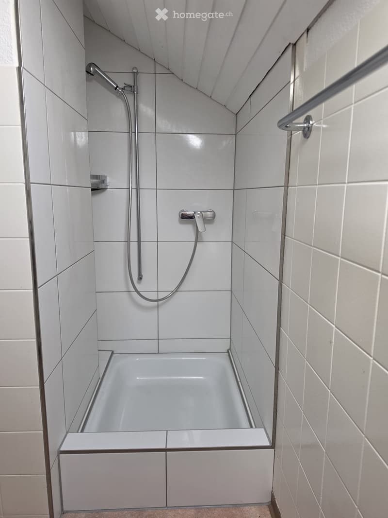 Modern bathroom with a bathtub, showerhead, and faucet, featuring white tiled walls and a sleek design.