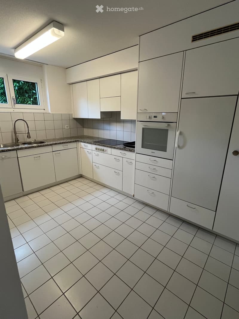 Modern kitchen with white cabinets, tiled floor, sink, faucet, oven, and refrigerator.