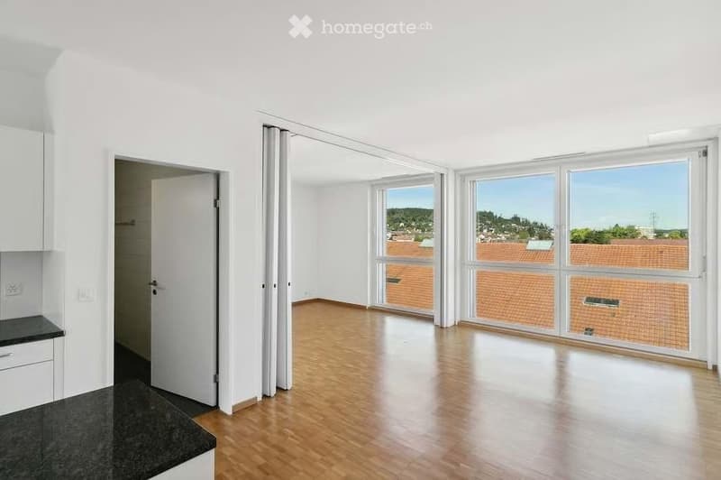 Empty room with wooden flooring, large windows, and white walls. No furniture or equipment present.