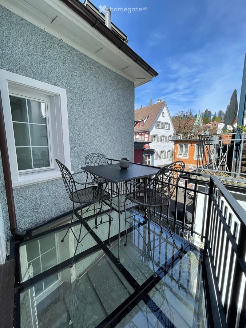 Table with chairs on a balcony with a glass floor overlooking the city