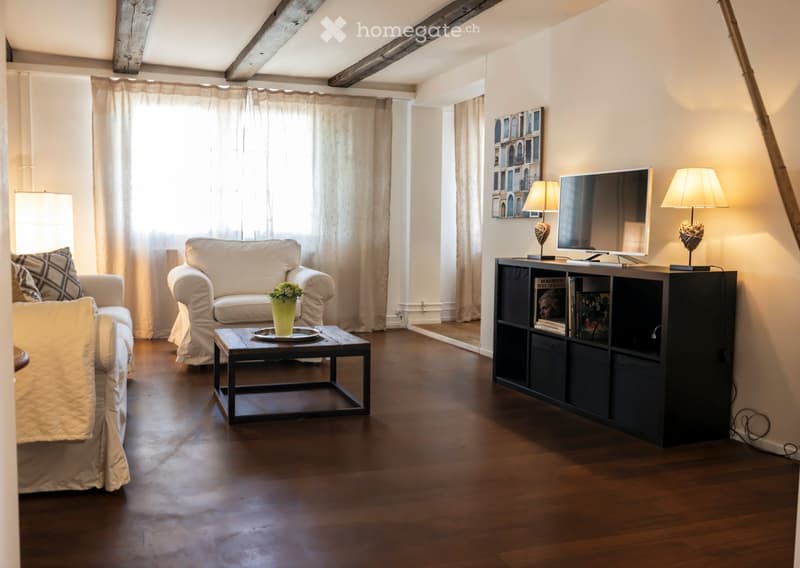 Living room with white sofa, coffee table, wooden floor, and large window with curtains